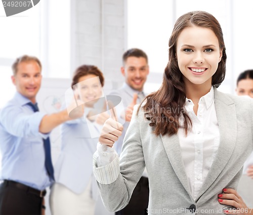 Image of businesswoman showing thumbs up in office