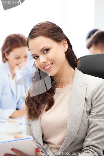 Image of attractive businesswoman taking notes in office