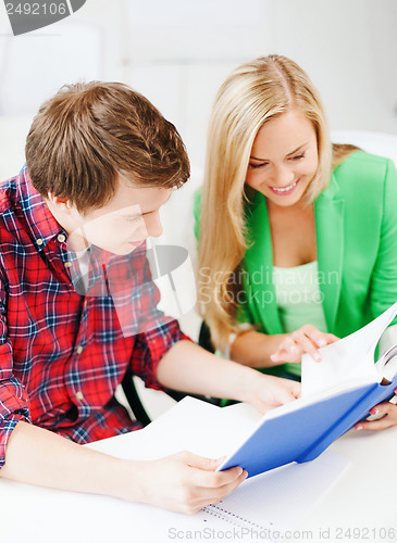 Image of smiling students reading book at school