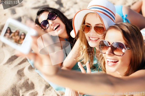 Image of girls making self portrait on the beach