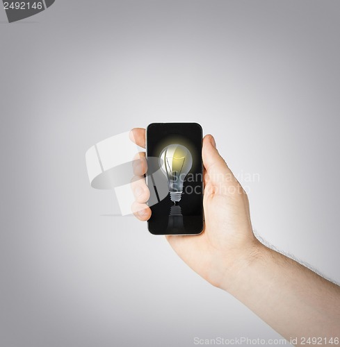 Image of man hand holding smartphone with light bulb