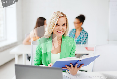 Image of smiling young girl reading book at school