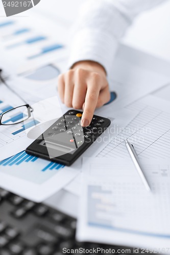 Image of woman hand with calculator and papers