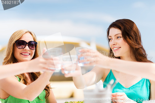 Image of girls making a toast in cafe on the beach