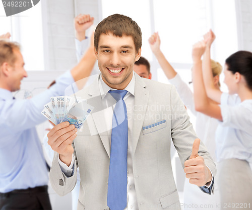 Image of happy businessman with cash money in office