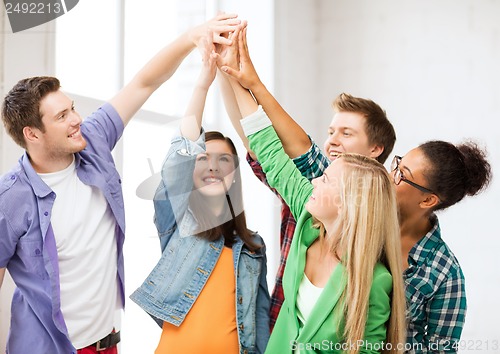 Image of happy students giving high five at school