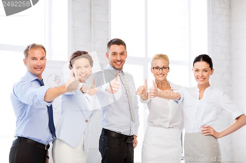 Image of business team showing thumbs up in office