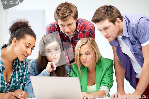 Image of international students looking at laptop at school