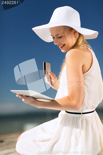 Image of woman in hat doing online shopping outdoors