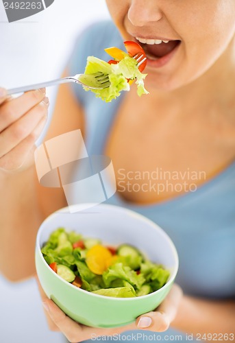 Image of woman eating salad with vegetables