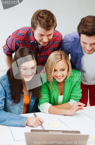 Image of smiling students looking at laptop at school