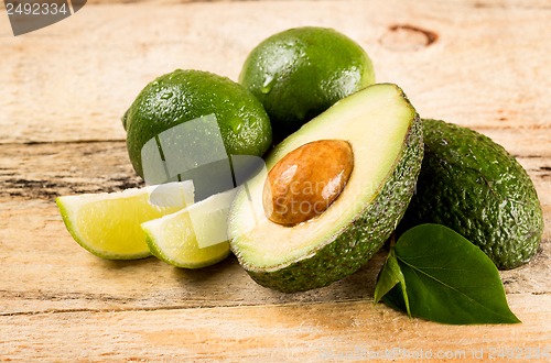 Image of avocado and limes on wooden background