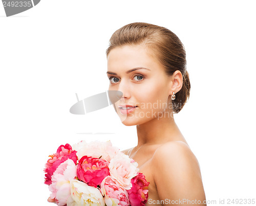 Image of woman wearing earrings and holding flowers