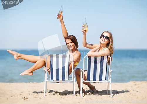 Image of girls sunbathing on the beach chairs