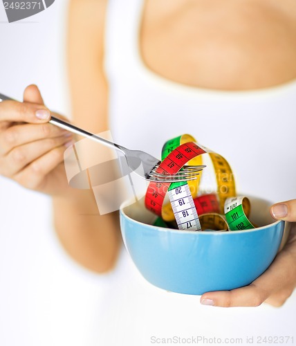 Image of woman hands holding bowl with measuring tape