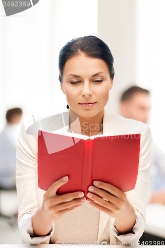Image of woman reading book in college or office