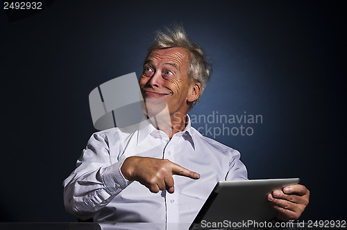 Image of Senior man grinning and pointing to his tablet