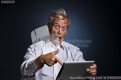 Image of Shocked senior man pointing to his tablet