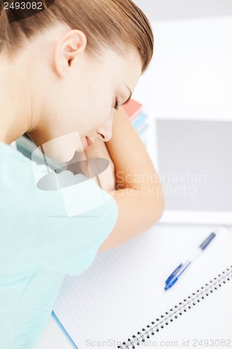 Image of tired student sleeping on stock of books