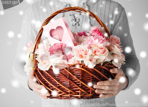 Image of man holding basket full of flowers and postcard