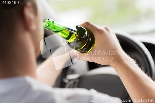 Image of man drinking alcohol while driving the car