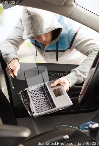 Image of thief stealing laptop from the car