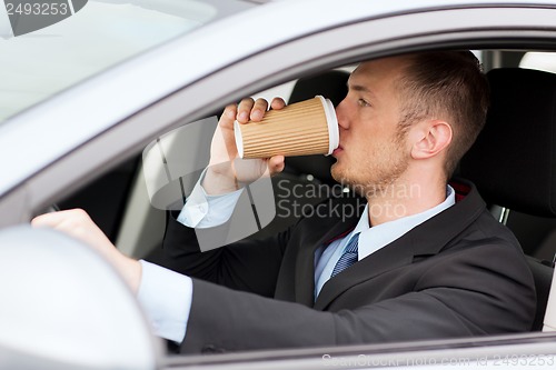 Image of man drinking coffee while driving the car