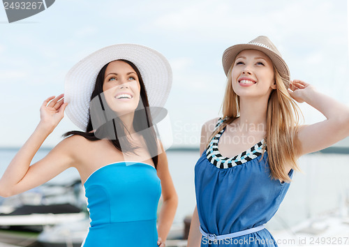 Image of girls in dresses with hats on the beach