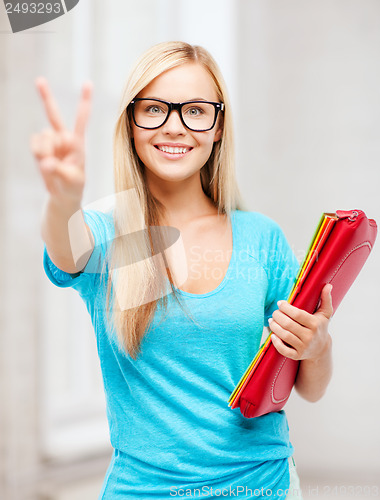 Image of smiling student with folders showing victory sign