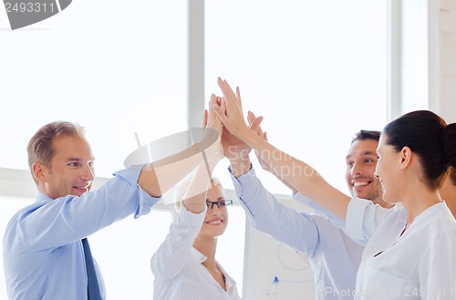 Image of happy business team giving high five in office