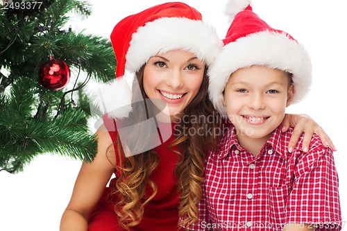 Image of happy mother and child boy in santa helper hats