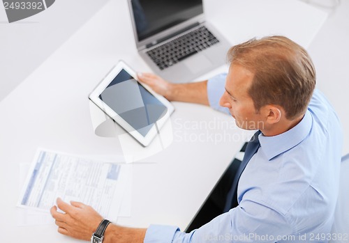 Image of businessman with tablet pc and papers in office