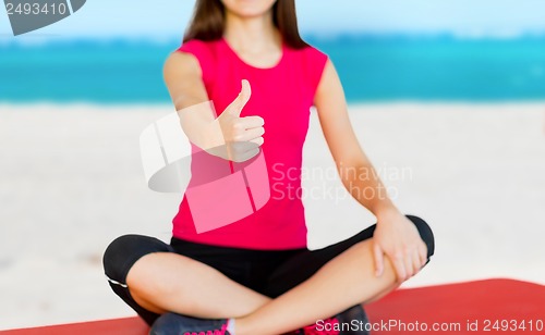 Image of girl sitting in lotus position with thumbs up