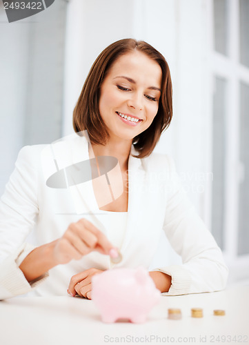 Image of woman putting coin into piggy bank