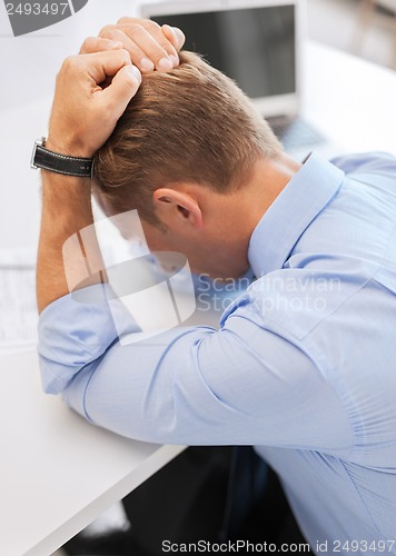 Image of stressed businessman with papers at work