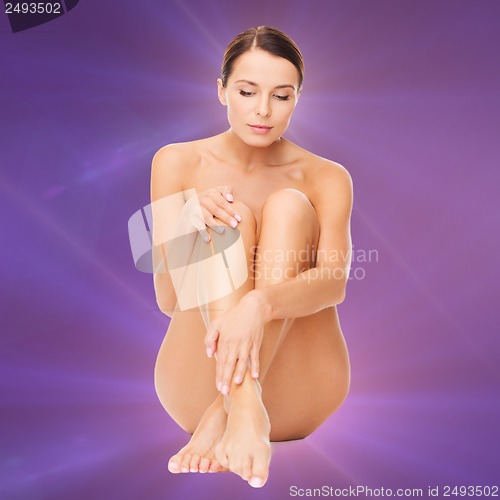 Image of beautiful naked woman touching her legs