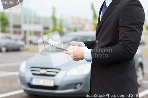 Image of man with car documents outside