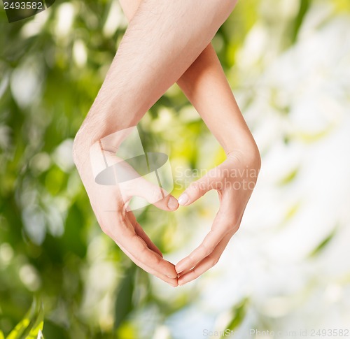 Image of woman and man hands showing heart shape