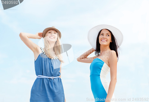 Image of girls in dresses with hats on the beach