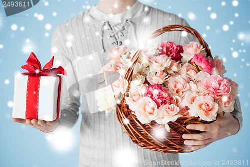 Image of man holding basket full of flowers and gift box