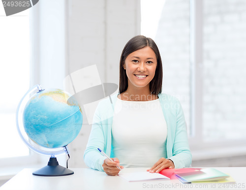 Image of teacher with globe and notepad at school