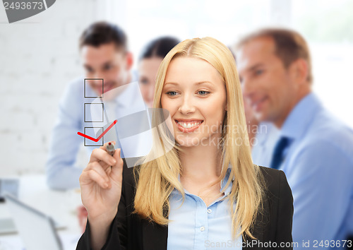 Image of businesswoman drawing checkmark on virtual screen