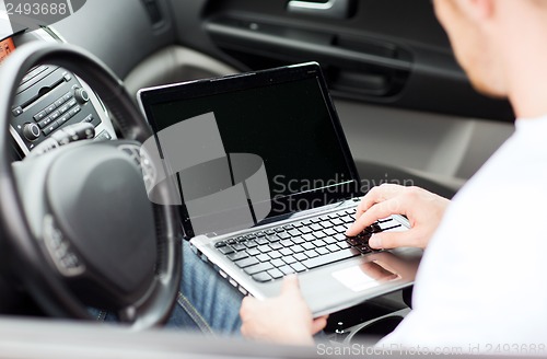 Image of man using laptop computer in car