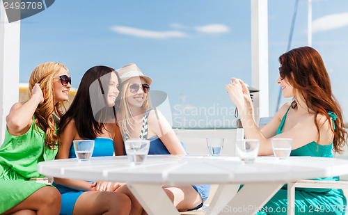 Image of girls taking photo in cafe on the beach