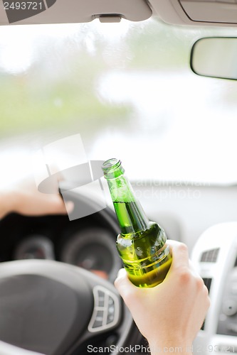 Image of man drinking alcohol while driving the car