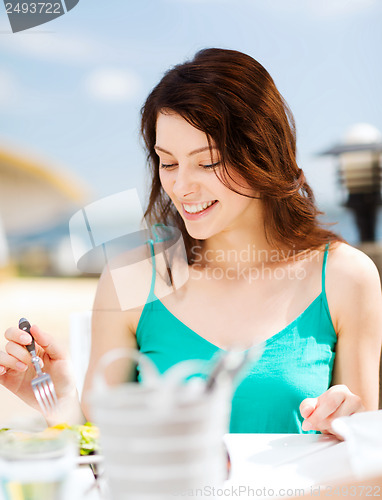 Image of girl eating in cafe on the beach