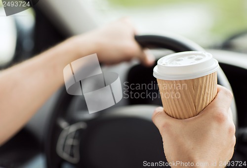 Image of man drinking coffee while driving the car