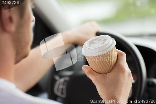 Image of man drinking coffee while driving the car