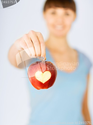 Image of woman hand holding red apple with heart shape