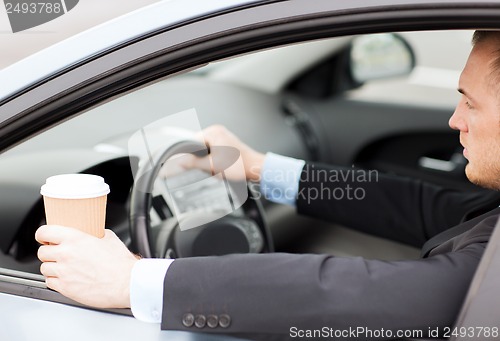 Image of man drinking coffee while driving the car